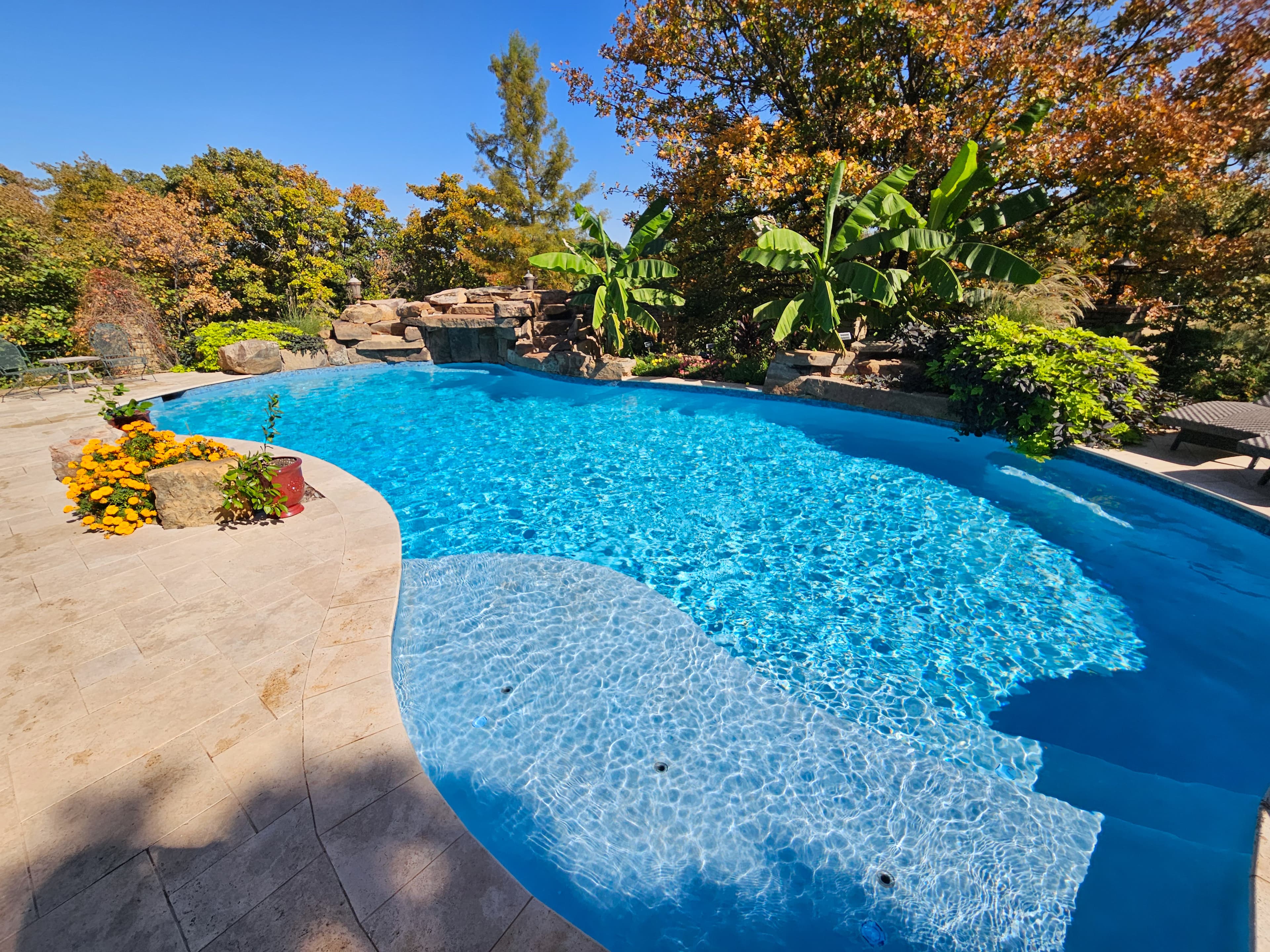 Crystal clear freeform pool with waterfall and lush landscaping